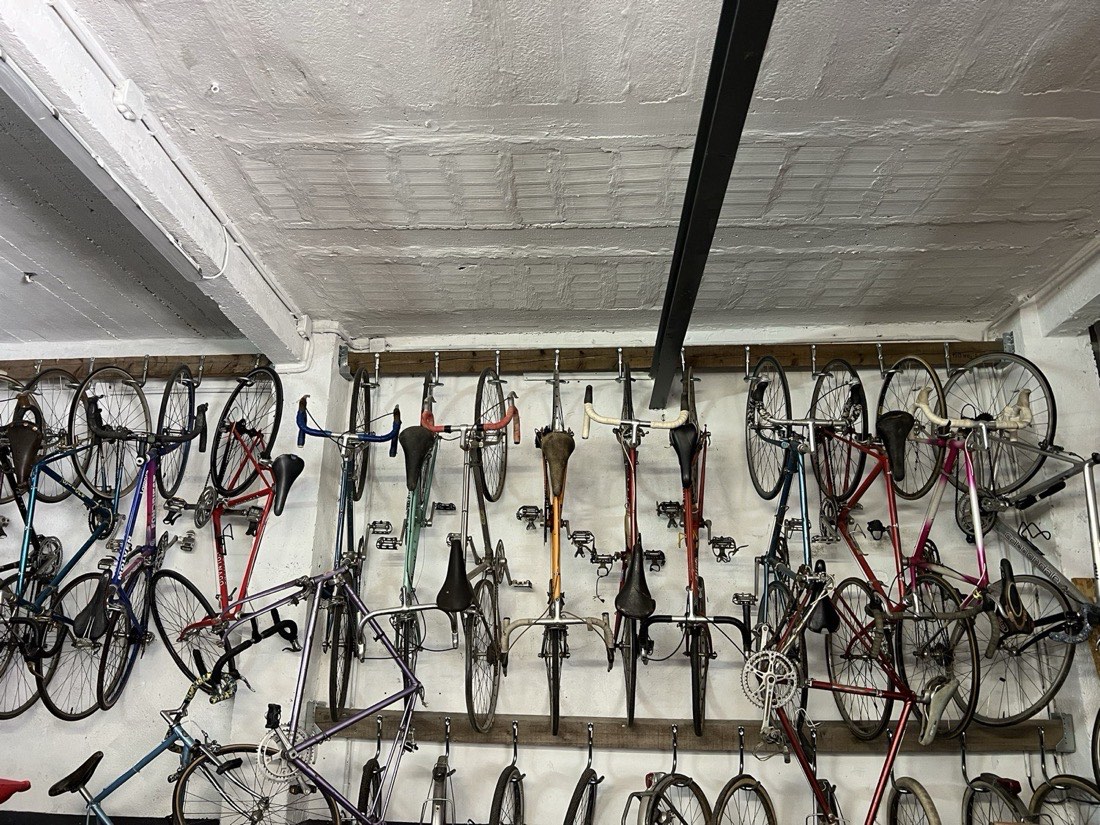 Mur de vélos de course vintage suspendus dans l’atelier Vélo-Cité à Avignon